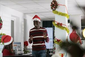 Multiracial business team enjoying job shift break, laughing together in festive decorated boardroom during holiday season. Employees feeling Christmas spirit mood, having fun in xmas adorn office photo