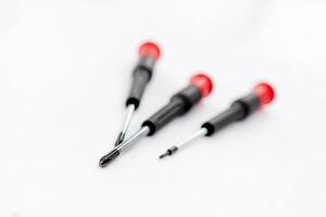 Close-up photoshoot of three red and black handled screwdrivers on a white background photo