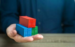 A man holds shipping containers in his hand. Joint orders. Cost savings due to bulk purchases or shared shipping expenses. Retailers and Suppliers. Transport operators. Customs authorities. photo