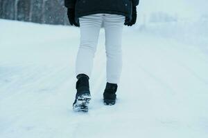 viajero caminando en el nieve, de cerca impermeable botas o Zapatos durante excursionismo en Nevado bosque. invierno temporada foto