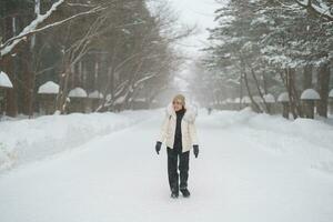 happy Traveler with Sweater and backpack walking on snow covered forest in frosty weather. Winter Travel, Adventure, Exploring and Vacation concept photo