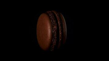 Chocolate macaroon on black background. Side view. Rotate 360 slow motion video