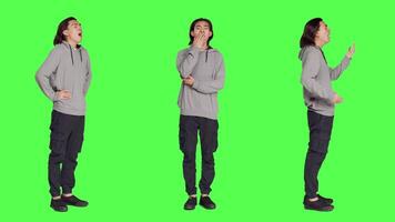 Young guy feeling sleepy and yawning after not getting enough sleep, posing with fatigue over full body greenscreen backdrop. Asian person being extremely tired and exhausted, falling asleep. video