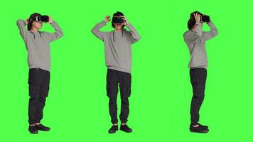 jovem cara usa virtual realidade tecnologia em Câmera com cheio corpo tela verde modelo, usando interativo 3d visão em vr óculos. moderno pessoa tendo Diversão com artificial inteligência fone de ouvido. video