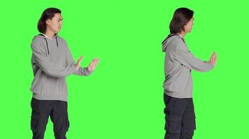 In studio, man tries to shove object aside, indicating rejection or resistance. Against blank greenscreen setting, young adult resembles refusal and disagreement with stop indication. video