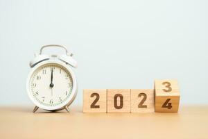 Happy New Year with vintage alarm clock and flipping 2023 change to 2024 block. Christmas, New Start, Resolution, countdown, Goals, Plan, Action and Motivation Concept photo