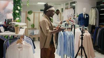 African american internet show host filming vlog in second hand clothing shop about helpful discounts. Fashion designer content creator in discount store recording for social media video