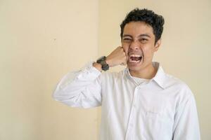 joven indonesio Rizado hombre vestir blanco ropa con golpear él yo pose. foto