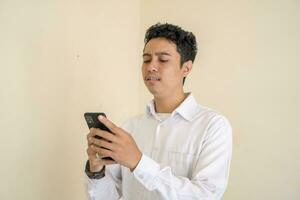 Indonesian man wear white clothes texting on smartphone. photo