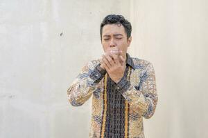 Young Indonesian wear batik traditional culture Indonesia with cough gesture. photo