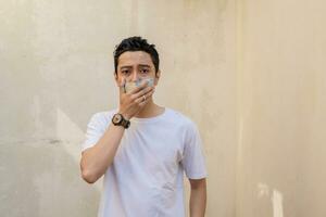 Indonesian man pose and gesture with shut up the mouth with money. photo