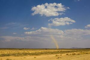 Whirlwind kick up dust on the plain in the desert photo