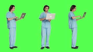 Young nurse reading patient information on pc, using wireless computer before starting healthcare checkup at clinic. Man assistant working in medical industry, using laptop on greenscreen. video