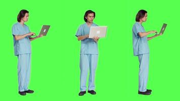 Young nurse reading patient information on pc, using wireless computer before starting healthcare checkup at clinic. Man assistant working in medical industry, using laptop on greenscreen. video