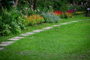 Background image of a garden path with colorful flowers planted beside it. photo