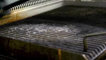 Cleaning a BBG grill in modern restaurant kitchen. Close up 4K footage video