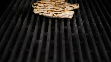 Pan up on fresh grilled piece of chicken breast meat on grill in restaurant kitchen video