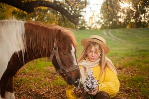 hermosa mujer y poni caballo en otoño bosque, puesta de sol luz, retrato, al aire libre recreación, amor y amistad. come flores foto