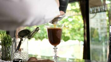 Close up bartender pouring a coffee cocktail in a glass video