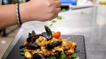 cocinero apretando fuera un limón terminado un plato con cocido Mariscos en restaurante cocina. lento movimiento video