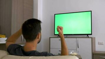 Mann Aufpassen ein groß Grün Attrappe, Lehrmodell, Simulation Bildschirm Fernseher im das Leben Zimmer. Dolly Schieberegler 4k Aufnahmen video
