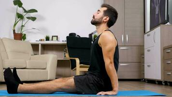 uomo rilassante nel diverso yoga pose su un' blu stuoia su il pavimento di il suo Casa. dolly cursore 4k metraggio video