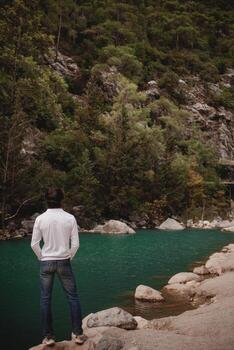 Man on the background of a mountain lake, tranquility and unity with nature in Turkey. stand photo
