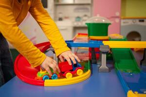 child in kindergarten, playroom, playing with toys, learning. Plays with car, race track, constructor. hands, close up. photo