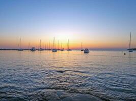 Picture of a marina with sailing ships in the backlight of the setting sun photo