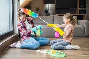 Happy mother and daughter having fun while cleaning  house together photo