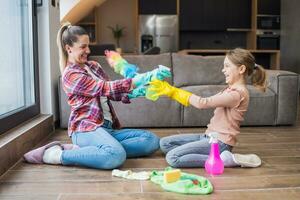 Happy mother and daughter having fun while cleaning  house together photo