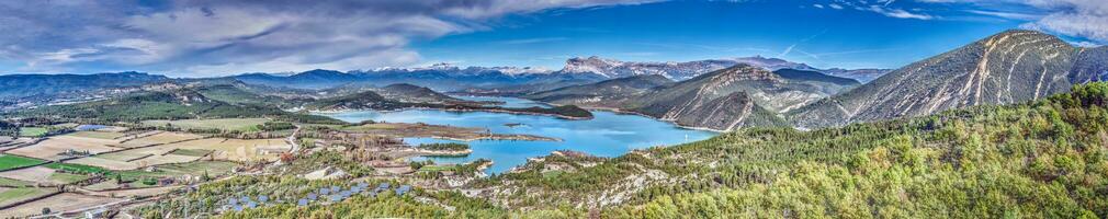 Drone panorama over the Mediano reservoir in the Spanish Pyrenees with snow-covered mountains in the background photo