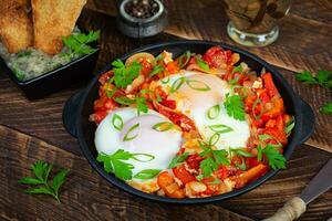 shakshuka con A la parrilla un pan. frito huevos con tomate, pimienta, ajo y hierbas foto