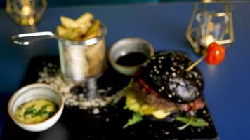 heerlijk Hamburger in zwart broodjes Aan restaurant tafel. van top visie zoom in naar dichtbij omhoog. 4k beeldmateriaal video