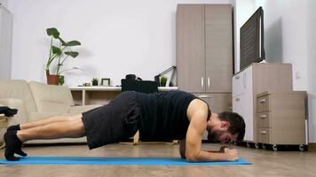 Man doing different exercises on a blue mat on the floor of his living room video