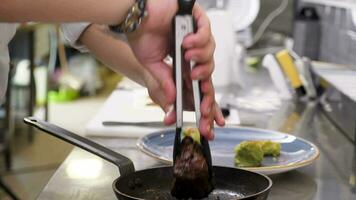 Cook taking a grilled beef steak from the pan and putting it aside video