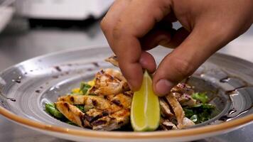 Cook hands placing a piece of lime on avocado salad with grilled meat and seasoning it with seeds video