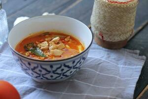 Chicken panang curry in a Thai style dish served on a black wooden table. photo