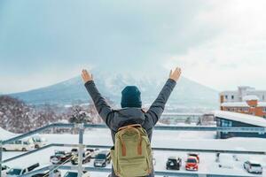 Woman tourist Visiting in Niseko, Traveler in Sweater sightseeing Yotei Mountain with Snow in winter season. landmark and popular for attractions in Hokkaido, Japan. Travel and Vacation concept photo