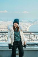 mujer turista visitando en hakodate, viajero en suéter Turismo ver desde hakodate montaña con nieve en invierno. punto de referencia y popular para atracciones en Hokkaidō, japon.viajes y vacaciones concepto foto