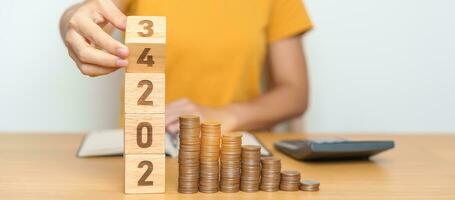 flipping 2023 to 2024 year block with Coins stack. Money, Budget, tax, investment, financial, savings and New Year Resolution concepts photo