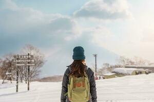 Woman tourist Visiting in Niseko, Traveler in Sweater sightseeing Yotei Mountain with Snow in winter season. landmark and popular for attractions in Hokkaido, Japan. Travel and Vacation concept photo