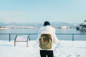 mujer turista visitando en hakodate, viajero en suéter Turismo hakodate Puerto cerca rojo ladrillo almacén con nieve en invierno. Hokkaidō, japon.viajes y vacaciones concepto foto