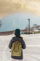 Woman tourist Visiting in Niseko, Traveler in Sweater sightseeing Yotei Mountain with Snow in winter season. landmark and popular for attractions in Hokkaido, Japan. Travel and Vacation concept photo