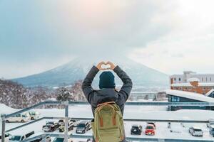 mujer turista visitando en niseko, viajero en suéter Turismo Yotei montaña con nieve en invierno estación. punto de referencia y popular para atracciones en Hokkaidō, Japón. viaje y vacaciones concepto foto