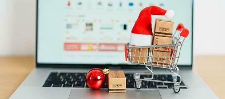 Christmas Online Shopping concept. Boxes with shopping cart on a laptop computer. Sale and discount during Christmas and New Year holiday, ecommerce, shipping delivery, logistics and Cyber Monday photo