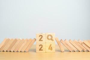 2024 year and falling blocks with magnifying glass icon. SEO, Search Engine Optimization, hiring , Advertising, Risk Management, recession, goal, New Year planning and inflation economy concepts photo