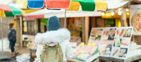 Woman tourist Visiting in Hakodate, Traveler in Sweater sightseeing Asaichi Morning Market Hakodate in winter. landmark and popular for attractions in Hokkaido, Japan. Travel and Vacation concept photo