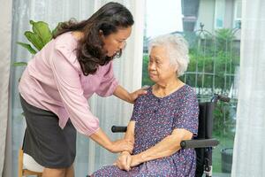 Caregiver help Asian senior woman on wheelchair with love at home. photo