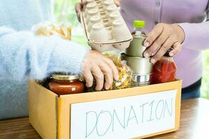 Volunteers putting various dry food in donation box for help people. photo